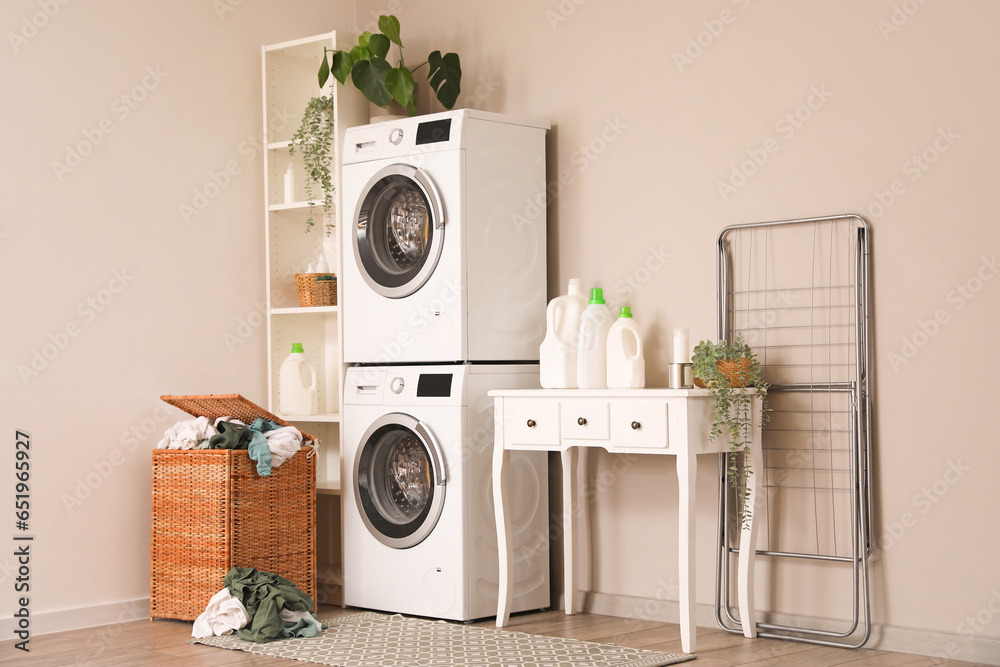 Interior of laundry room with washing machines, table and basket