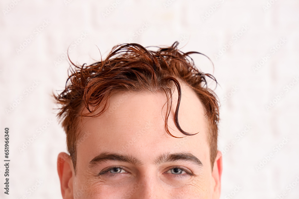 Young man with wet hair on white brick background