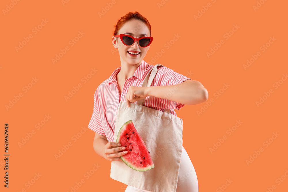 Young woman with fresh watermelon and bag on orange background