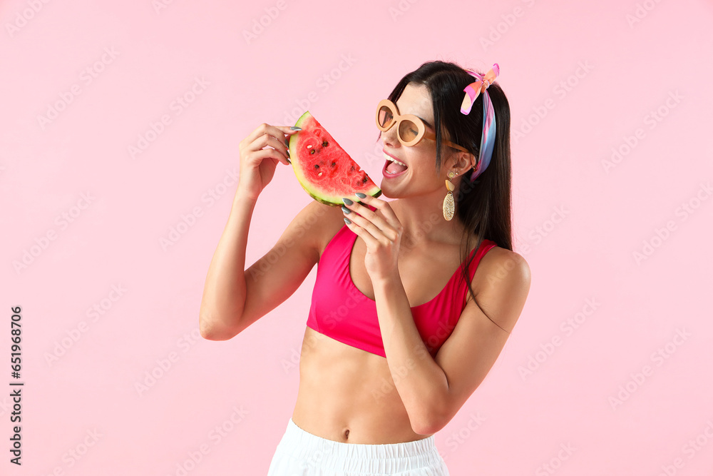 Young woman eating fresh watermelon on pink background