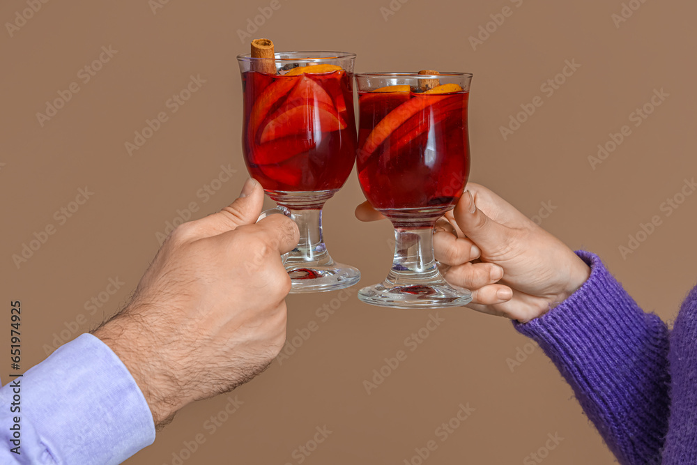 Young couple with glasses of mulled wine on color background, closeup