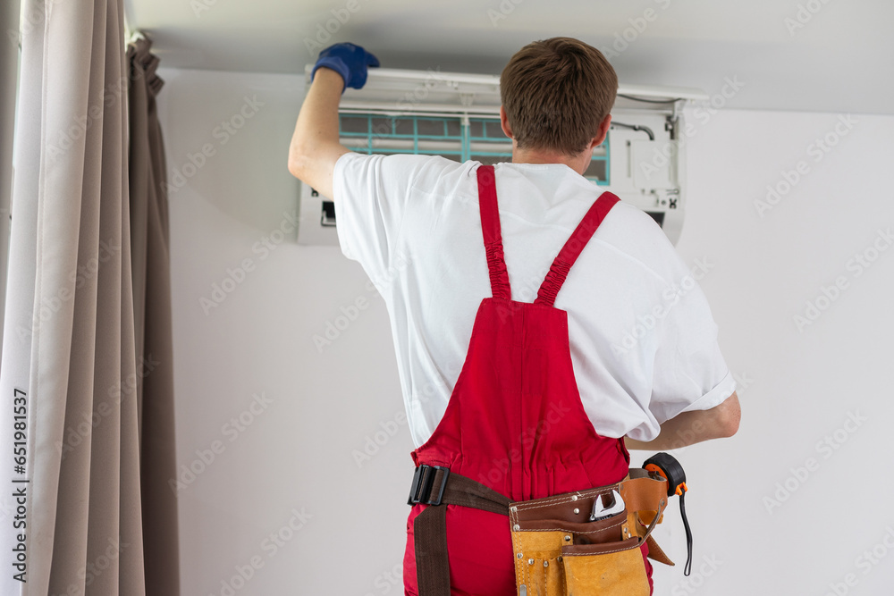 Professional technician maintaining modern air conditioner indoors.