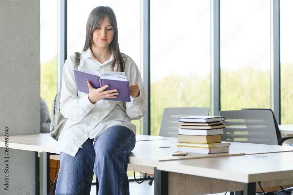 Portrait of a schoolgirl standing in the classroom with a book in her hands.