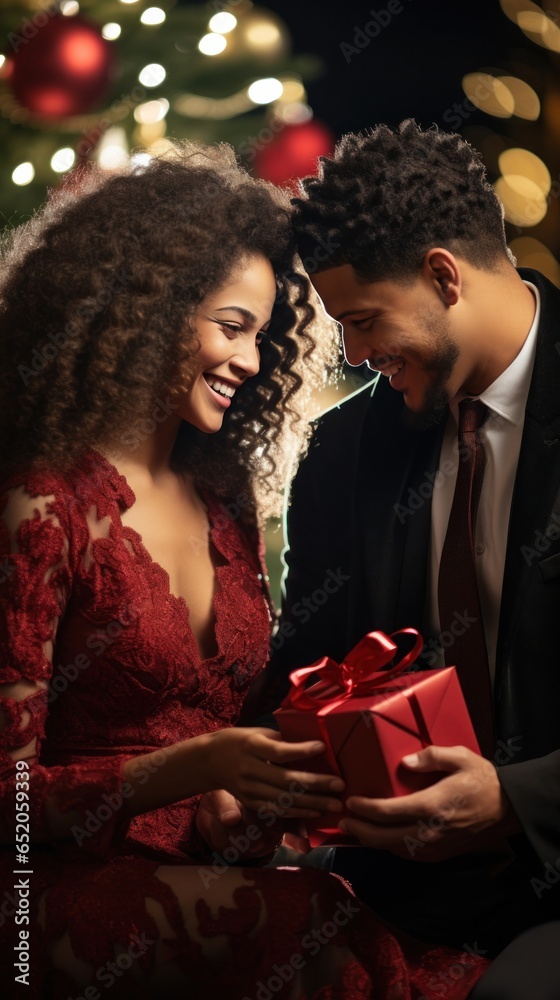 Smiling couple exchanging gifts near a decorated tree