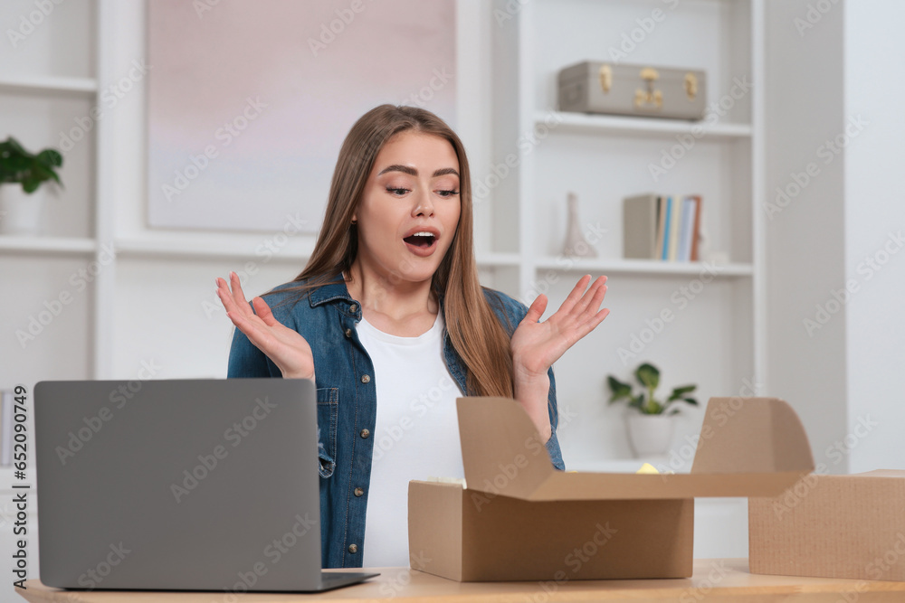 Emotional woman unpacking parcel at home. Online store