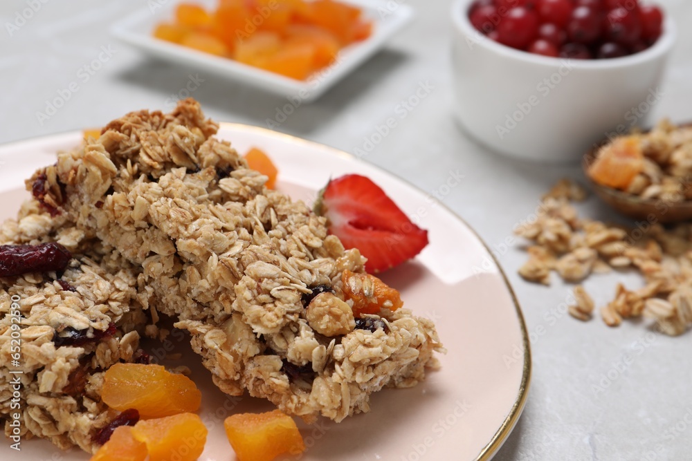 Tasty granola bars and ingredients on light grey table, closeup