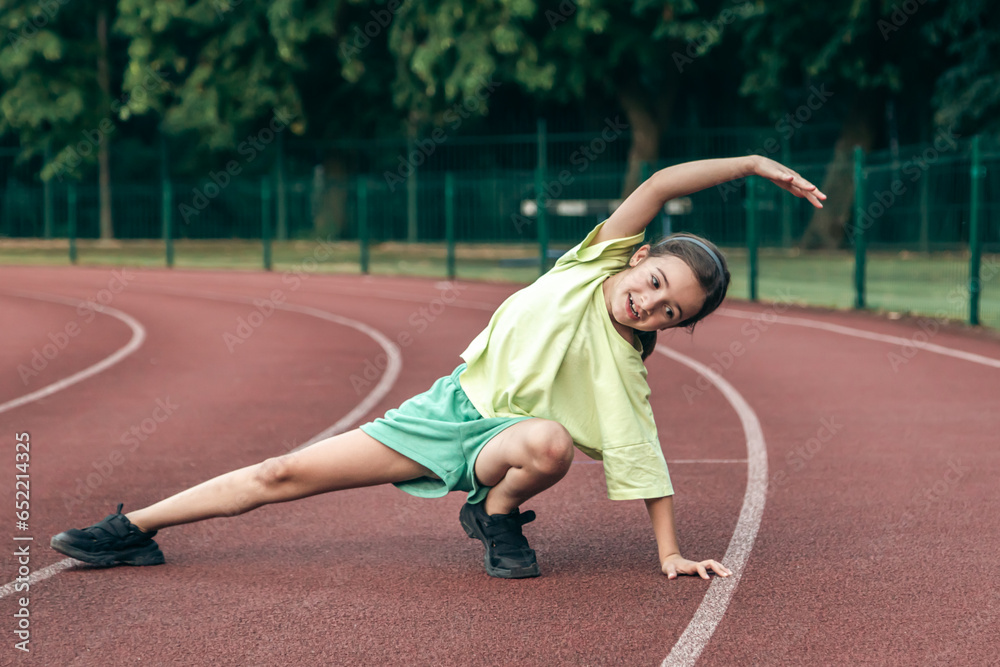 Child training at school physical lesson, teenage girl stretching outdoors.