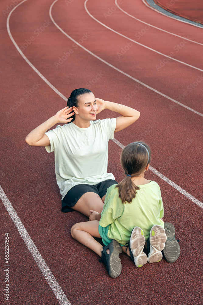 Mother and daughter go in for sports outdoors at the stadium.