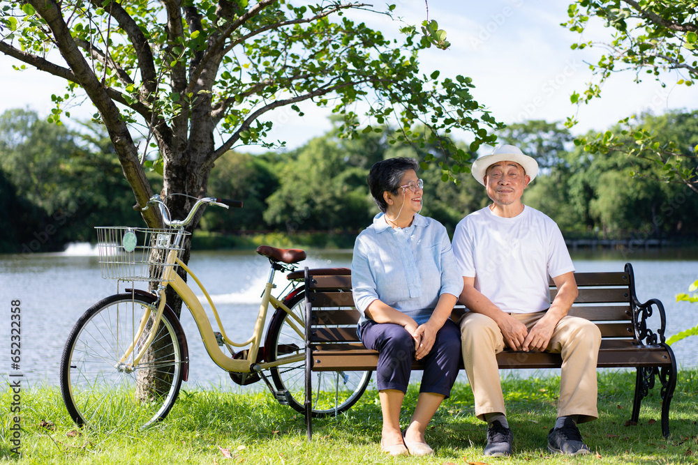 Happy and healthy couple Asian sitting chair beside a bicycle Family and friendship lifestyle, Enjoyment of active seniors, and outdoor activity after retirement, health care insurance concept