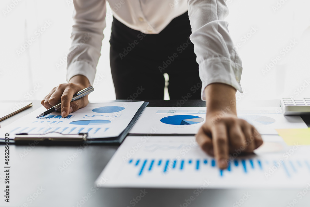 Businesswoman working on documents analyzing business finance charts and planning investments.