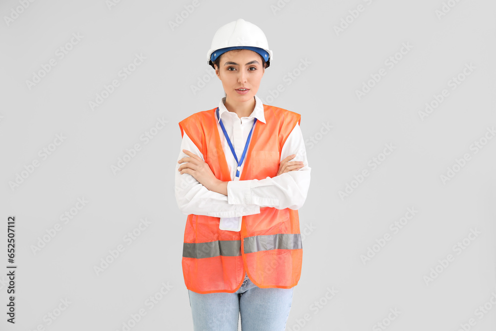 Female worker in vest on light background