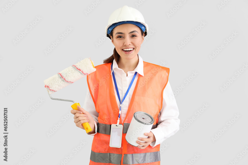 Female decorator with paint and roller on light background