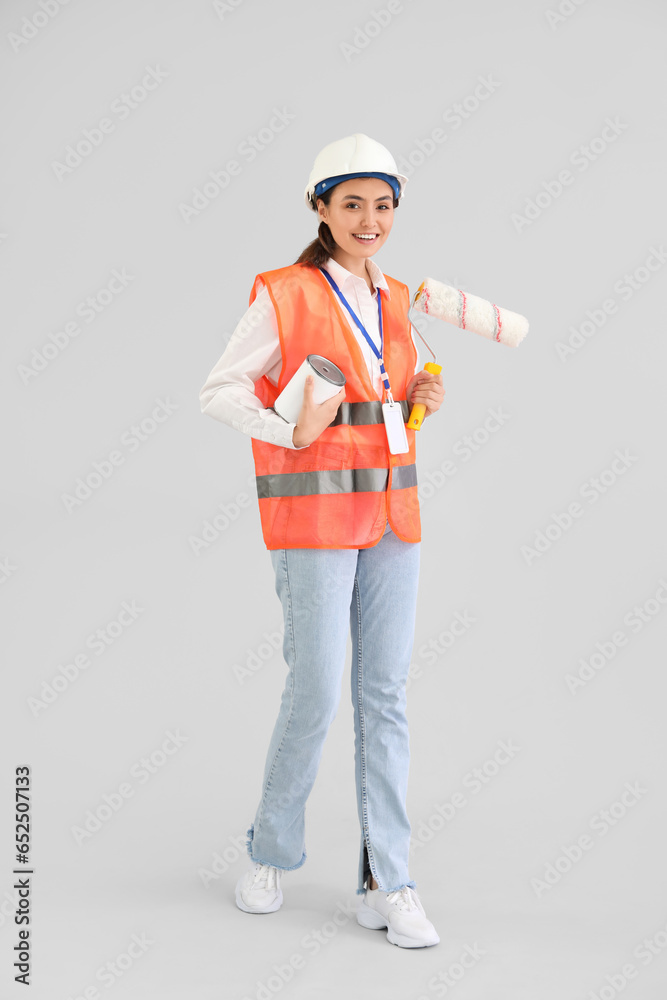 Female decorator with paint and roller on light background