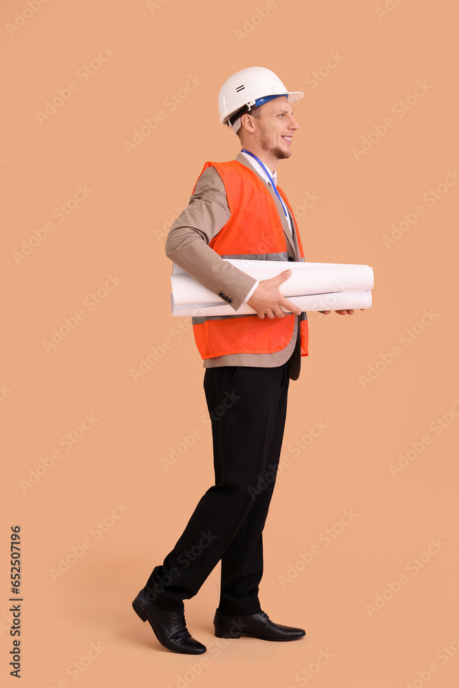 Male architect with drawing on beige background