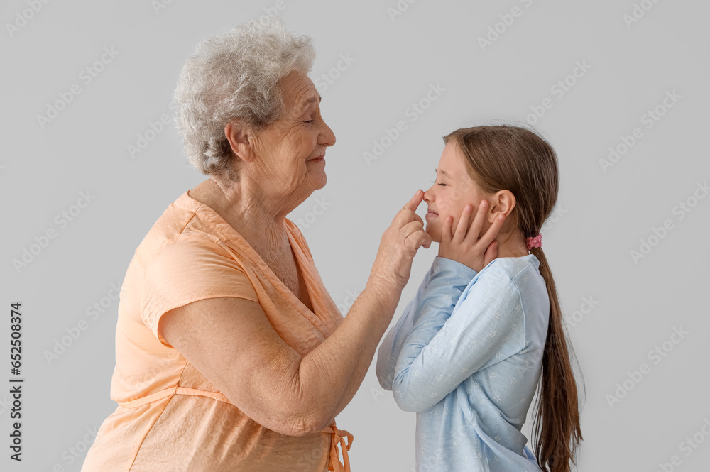 Little girl with her grandmother on grey background