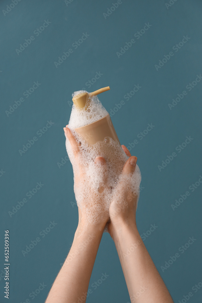 Hands with liquid soap on blue background