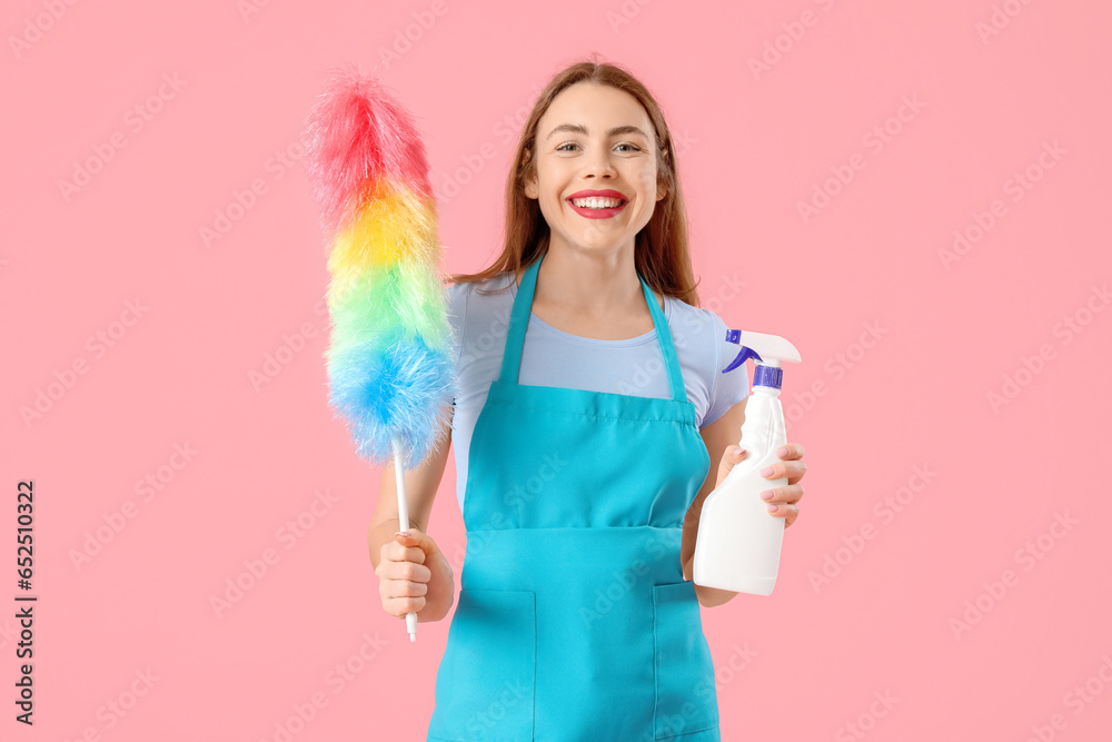 Young woman with bottle of detergent and pp-duster on pink background