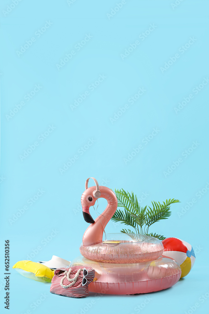 Creative composition with inflatable rings, plant and beach accessories on blue background. Summer vacation concept