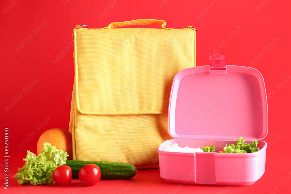 Bag and lunchbox with tasty food on red background