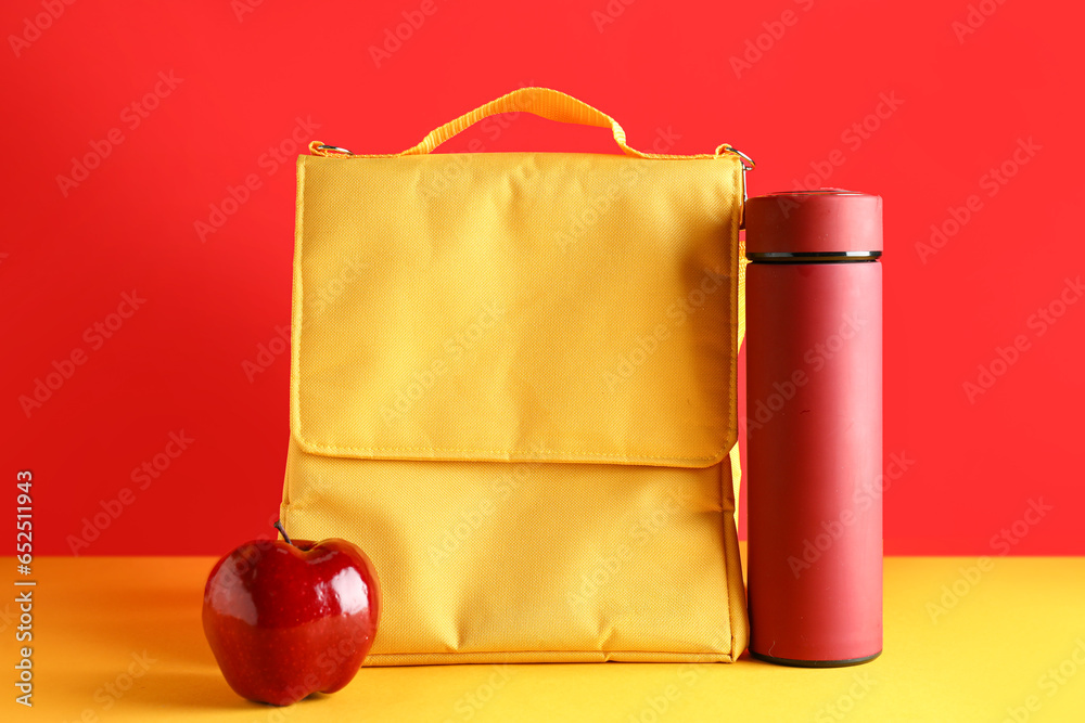 Lunch box bag with thermos and fresh apple on color background