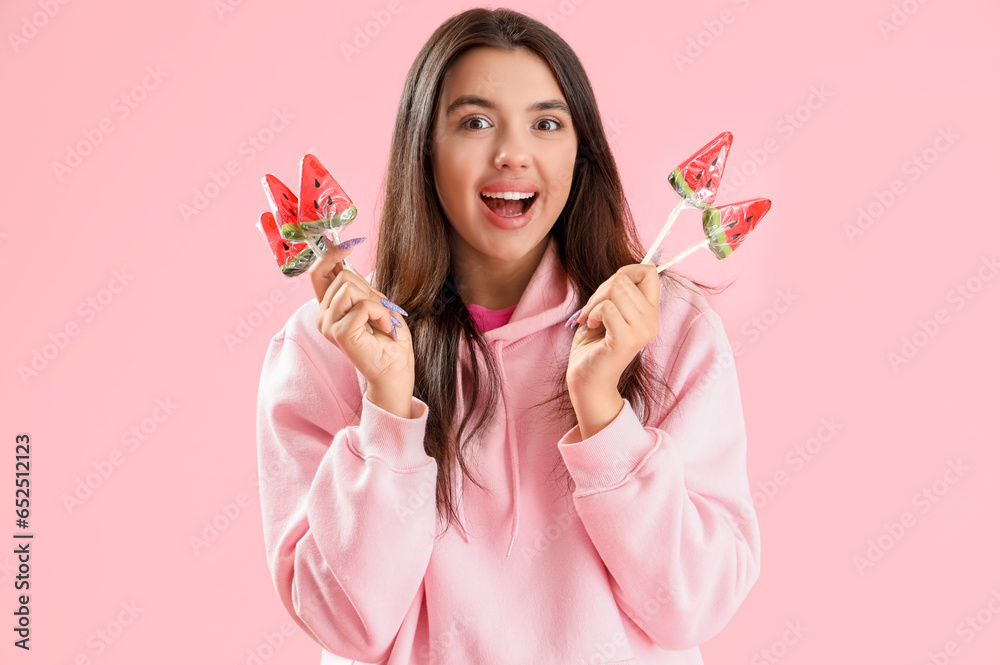 Beautiful happy young woman with watermelon lollipops on pink background