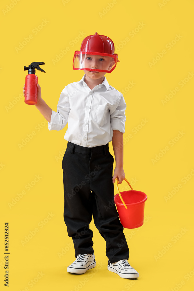 Cute little firefighter on yellow background