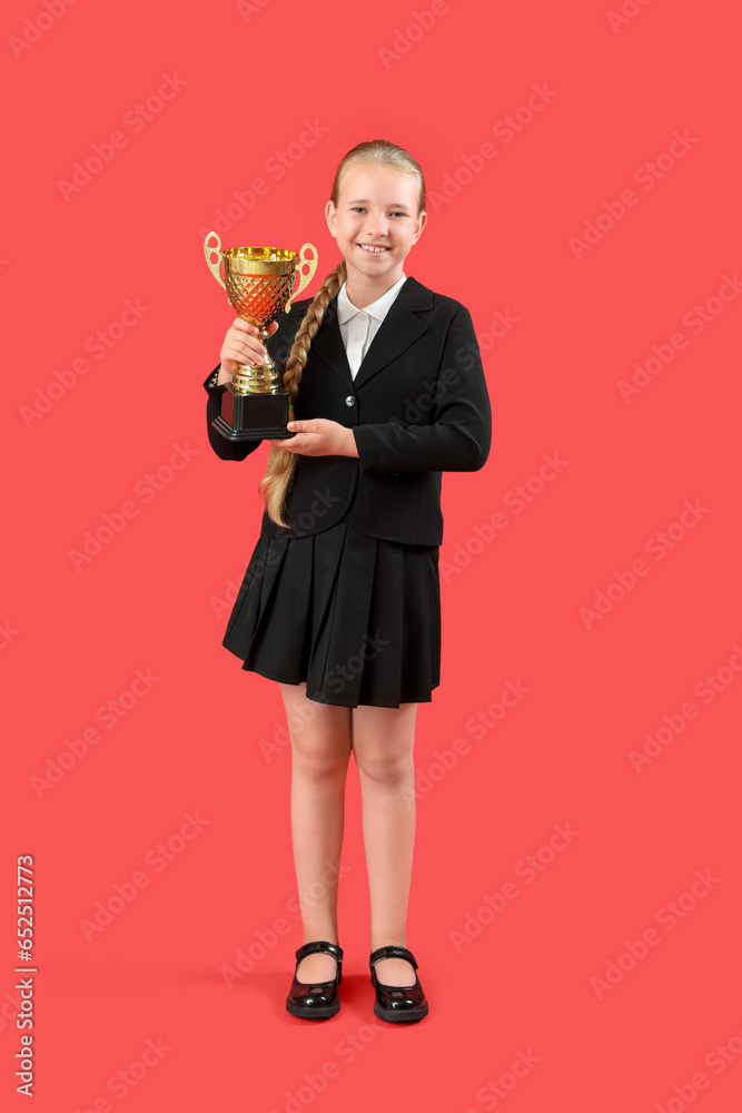 Cute little schoolgirl with gold cup on red background