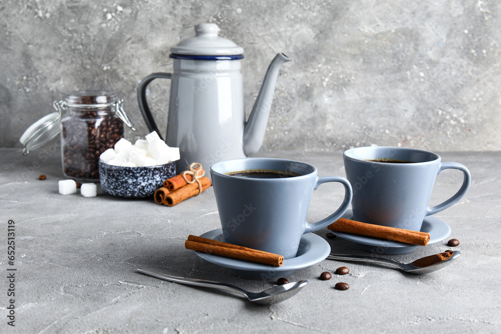 Cups of tasty coffee with cinnamon on grey background