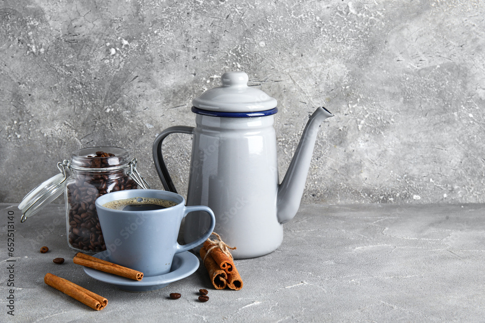 Cup of coffee with cinnamon, teapot and beans on grey background