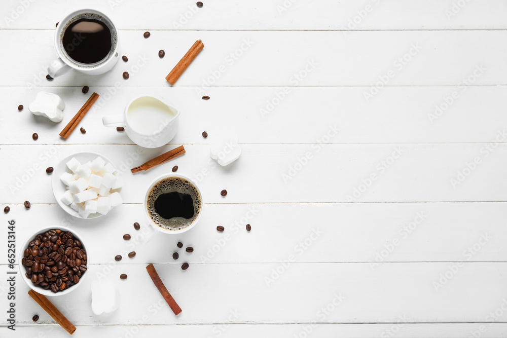 Cups of tasty coffee with cinnamon, milk, sugar, marshmallow and beans on white wooden background