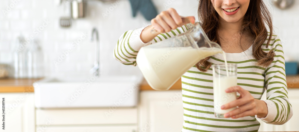 Portrait of beauty healthy asian woman smiling and having protein breakfast drinking and hold glasses of milk of fresh milk, nutrition,calcium and vitamin,dairy product in kitchen at home.Diet concept