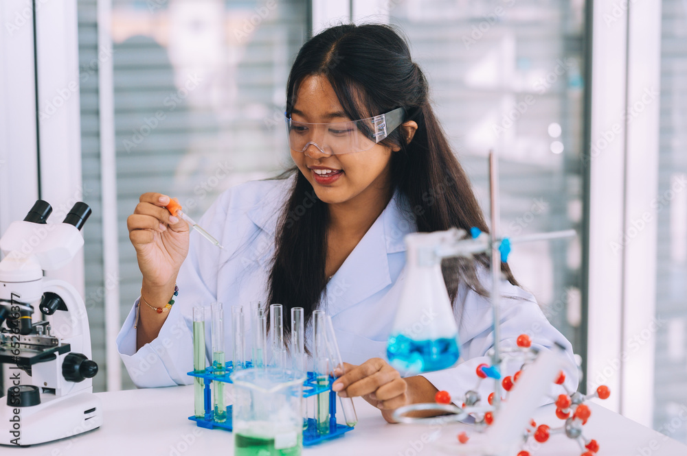 Cute little teenage student learns, researches and performs chemistry experiments while analyzing and mixing liquids in test tubes at the laboratory at school. Education