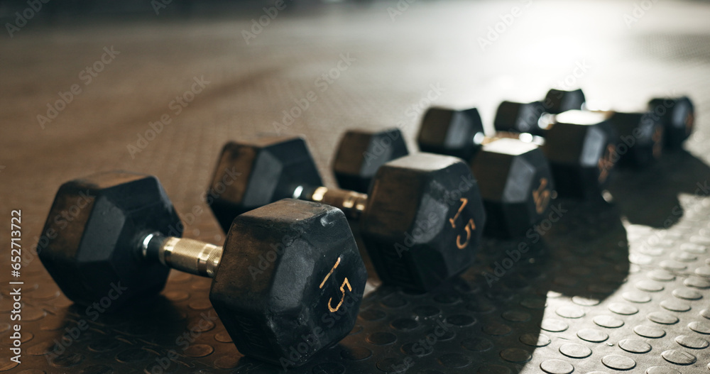 Fitness, background and dumbbells in empty gym for exercise, bodybuilding workout and sports training. Closeup of heavy steel weights, equipment and iron on floor in wellness club for muscle power