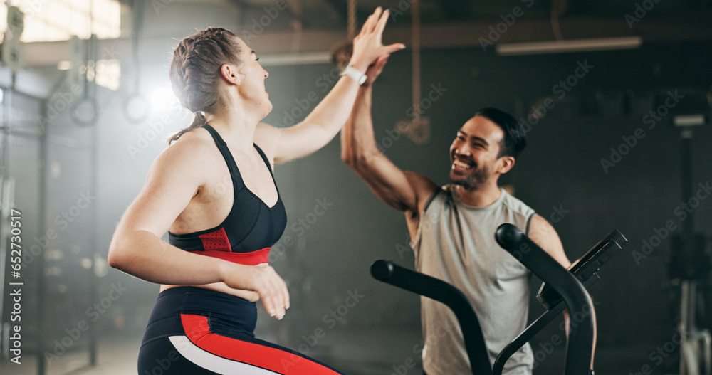 Woman, cycling and personal trainer in high five, motivation or fitness workout, exercise and training at gym. Man coaching female person on bicycle, machine or equipment in cardio at health club