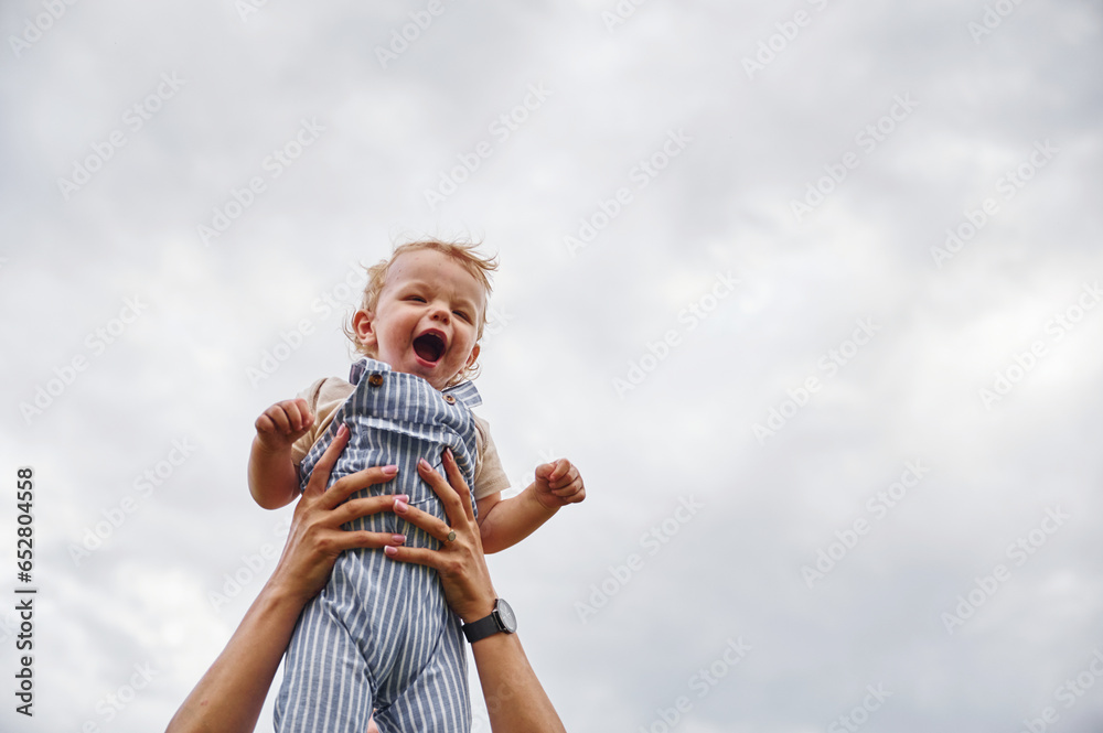 Cute and happy little boy is being holding by woman hands