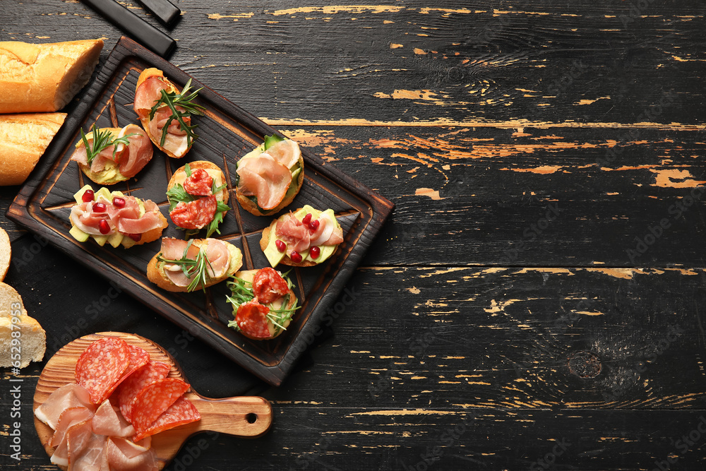 Boards of tasty bruschettas with ham on dark wooden background