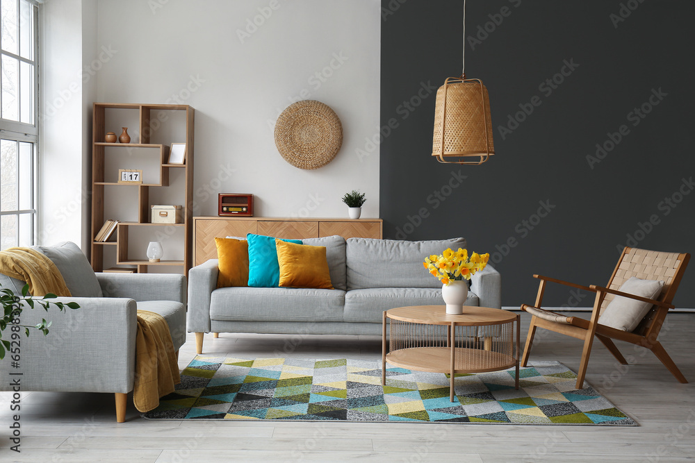 Interior of stylish living room with cozy sofa, armchairs and flower vase on coffee table