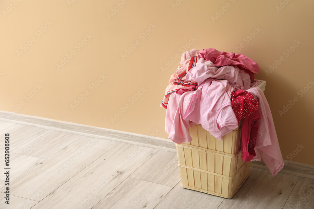 Basket with dirty clothes near beige wall