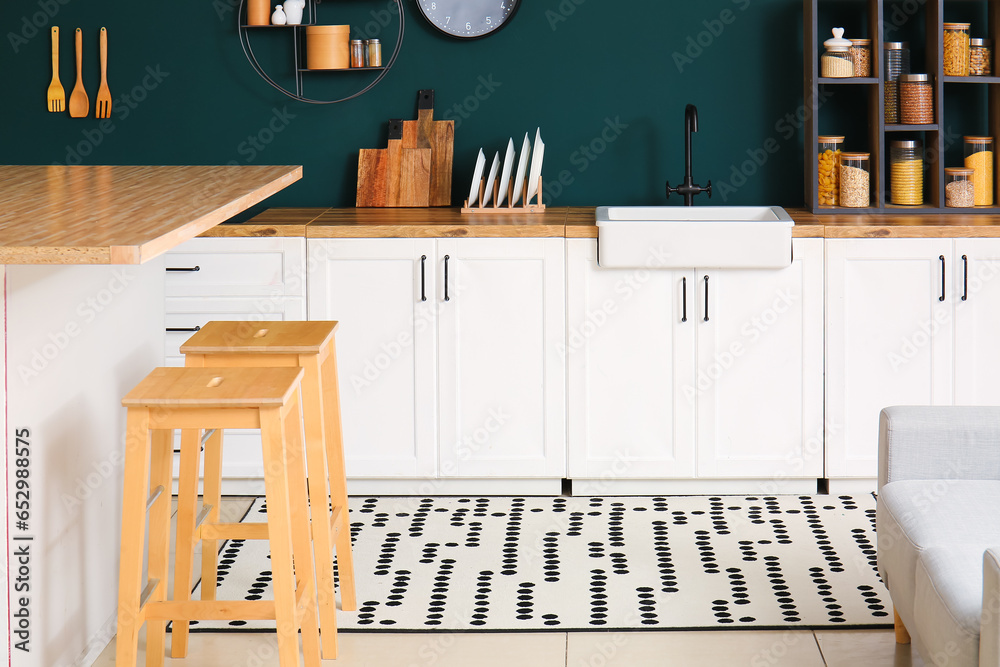 Interior of modern kitchen with wooden bar stools near table