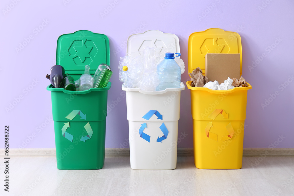 Containers with different types of garbage near lilac wall. Recycling concept