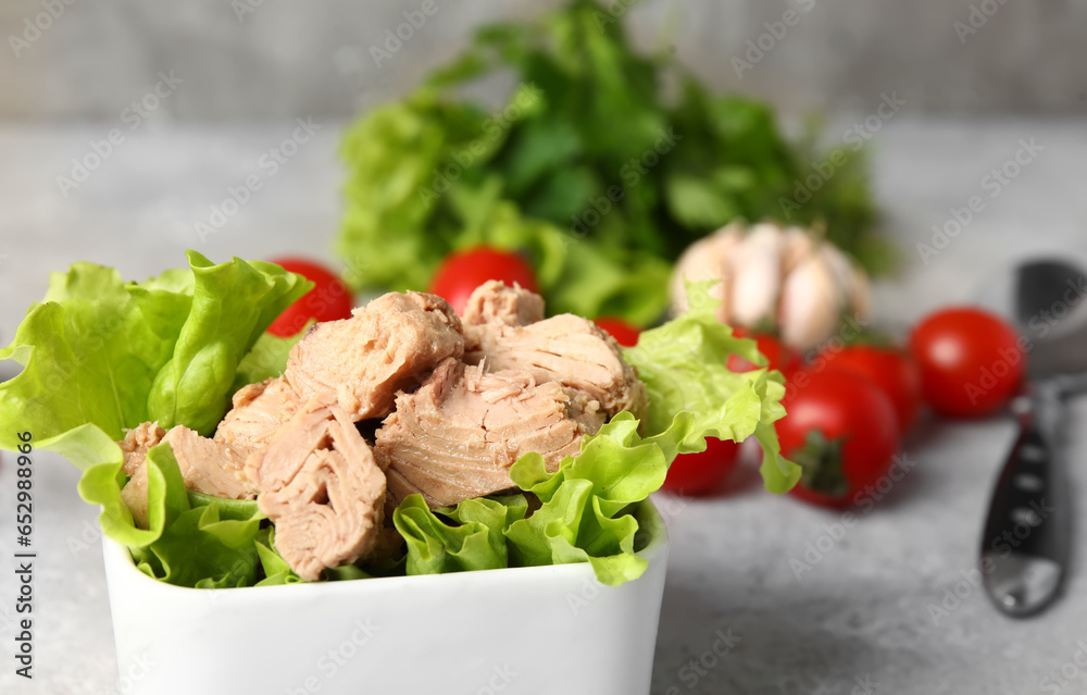 Bowl with delicious canned tuna and lettuce on white table