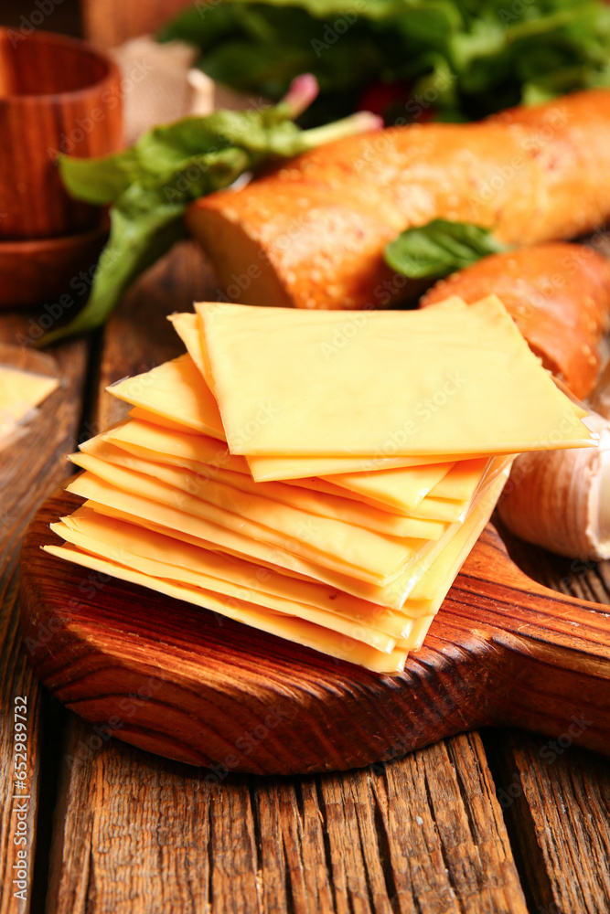 Wooden board with slices of tasty processed cheese on table