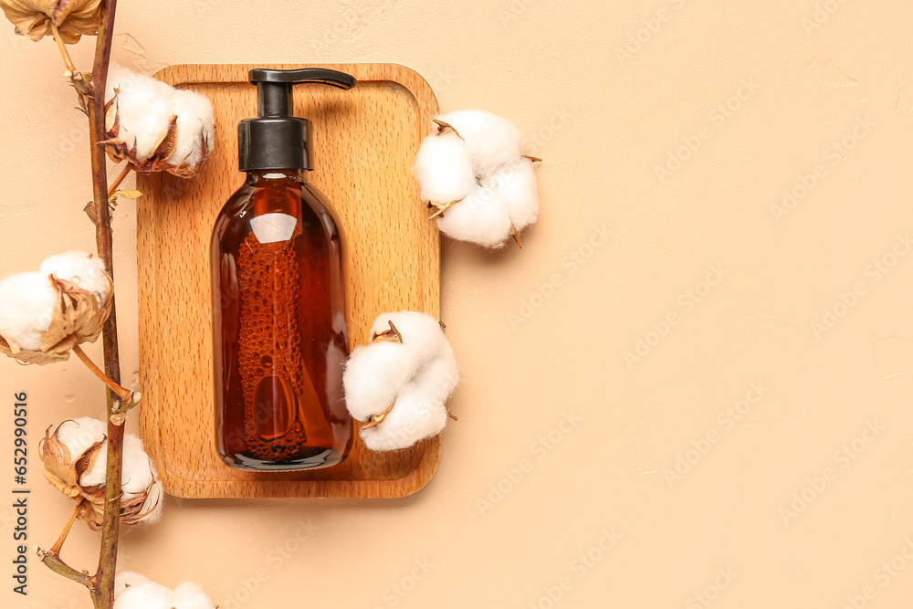 Wooden board with bottle of cosmetic product and cotton branch on color background