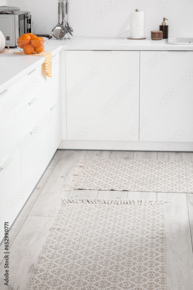 Stylish rug on floor in light kitchen