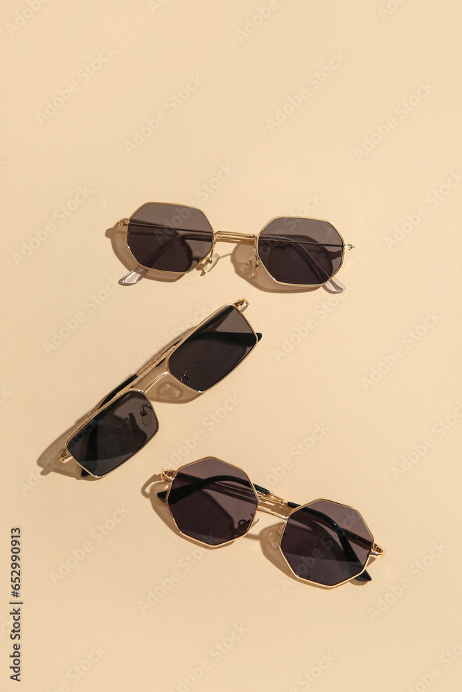 Different stylish sunglasses on beige background