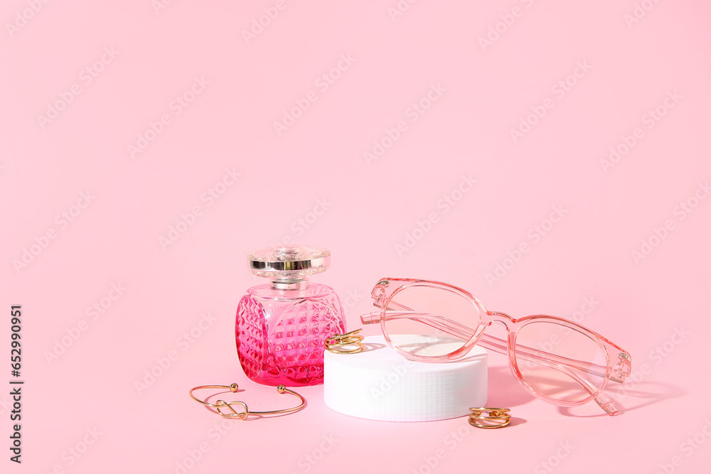 Podium with stylish sunglasses and perfume on pink background