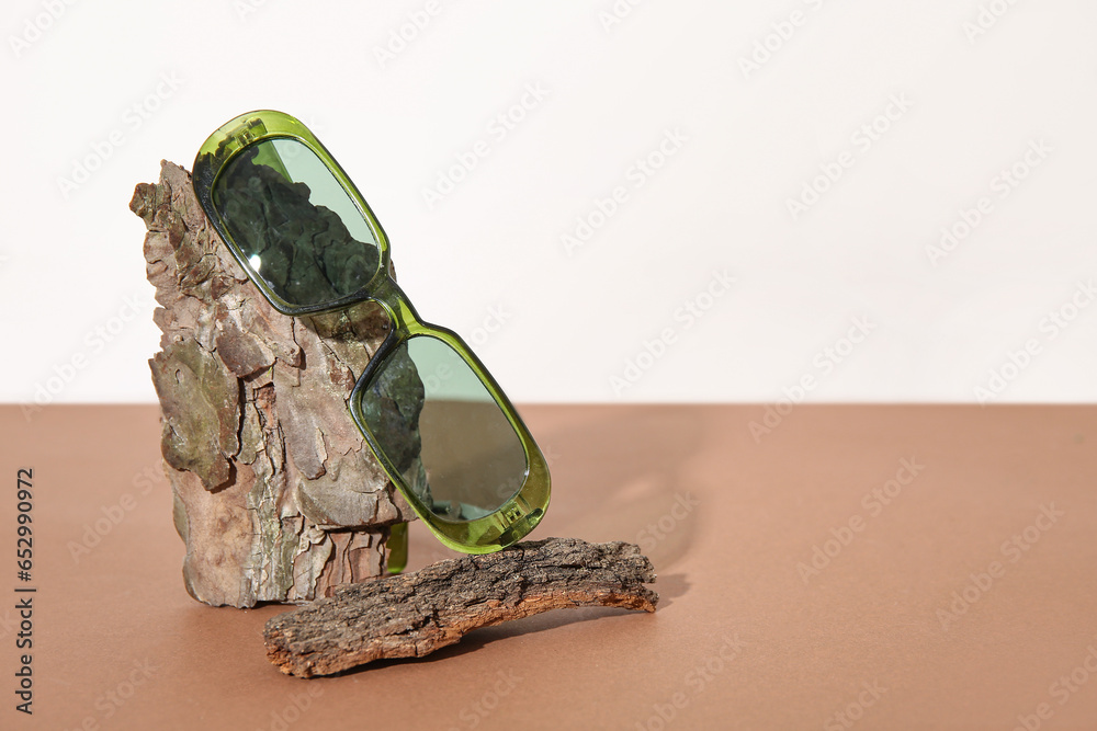 Tree bark with stylish sunglasses on brown table