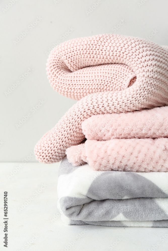 New soft folded blankets on table near light wall