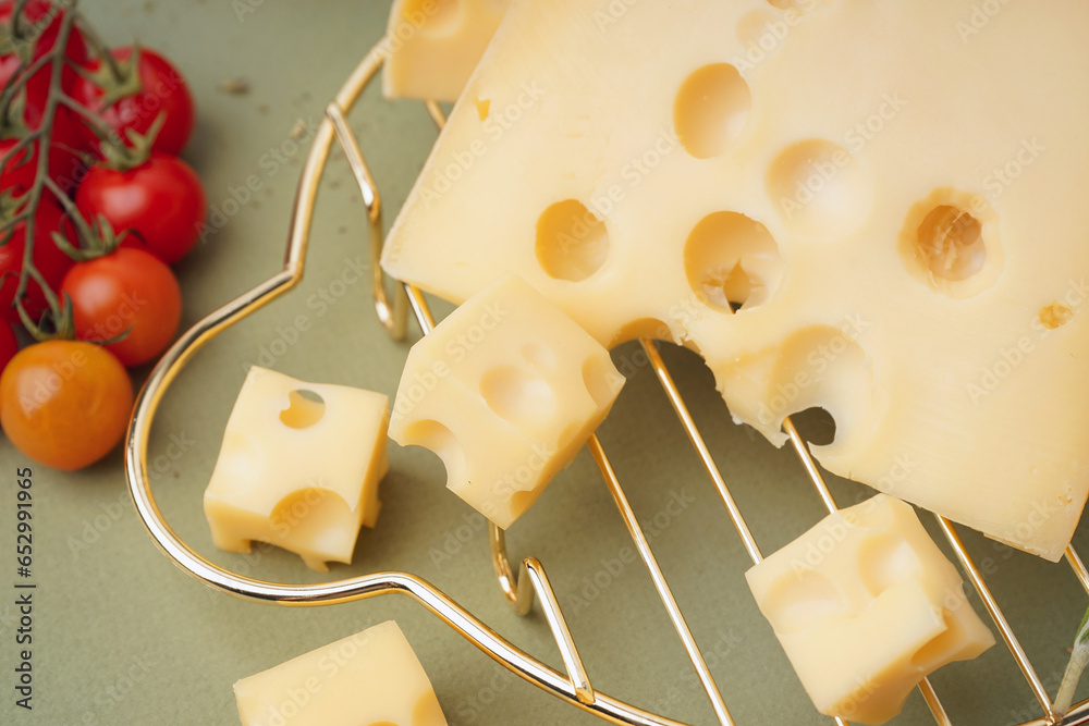 Stand with pieces of Swiss cheese and tomatoes on green background