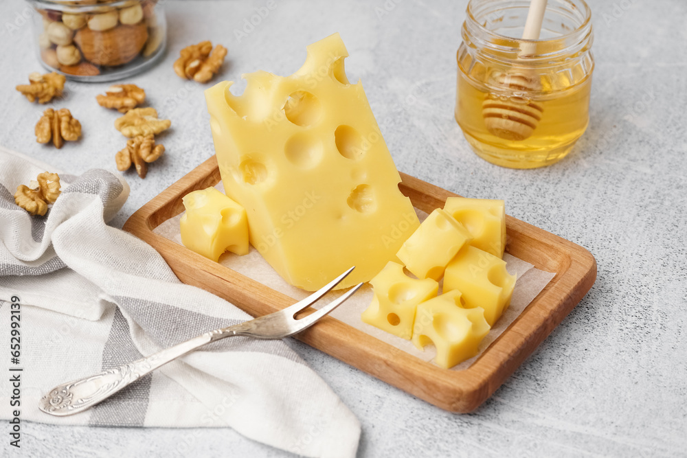 Board with pieces of Swiss cheese and honey on white table